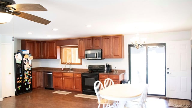 kitchen featuring a sink, black appliances, dark countertops, and dark wood-style floors