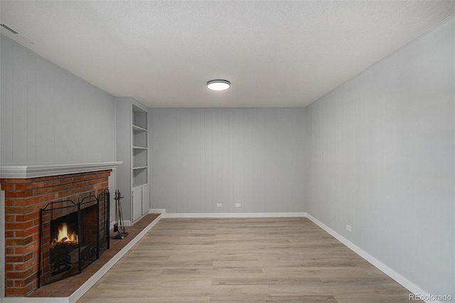 7165 S Gaylord St Unit H05, Centennial, CO 80122 - unfurnished living room with light wood-style floors, a fireplace, and built in features