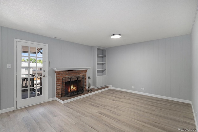 7165 S Gaylord St Unit H05, Centennial, CO 80122 - unfurnished living room featuring light wood finished floors, a brick fireplace, and a textured ceiling