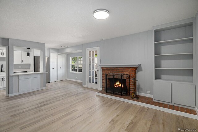 7165 S Gaylord St Unit H05, Centennial, CO 80122 - unfurnished living room with light wood-type flooring, a fireplace, and built in features