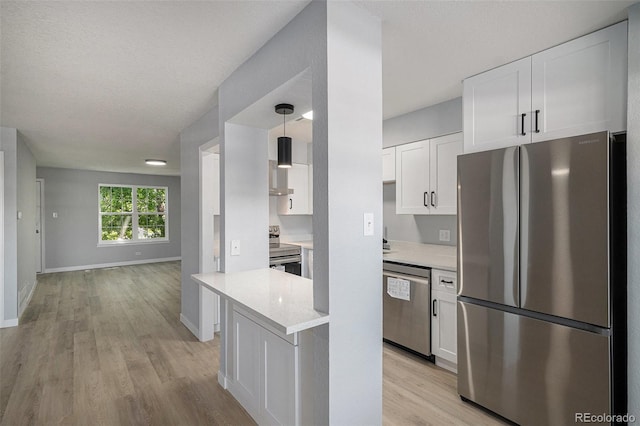 7165 S Gaylord St Unit H05, Centennial, CO 80122 - kitchen with stainless steel appliances, white cabinetry, light wood-style floors, open floor plan, and hanging light fixtures