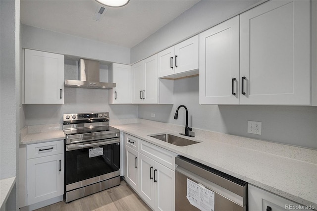 7165 S Gaylord St Unit H05, Centennial, CO 80122 - kitchen with appliances with stainless steel finishes, wall chimney exhaust hood, white cabinets, and light wood-style floors
