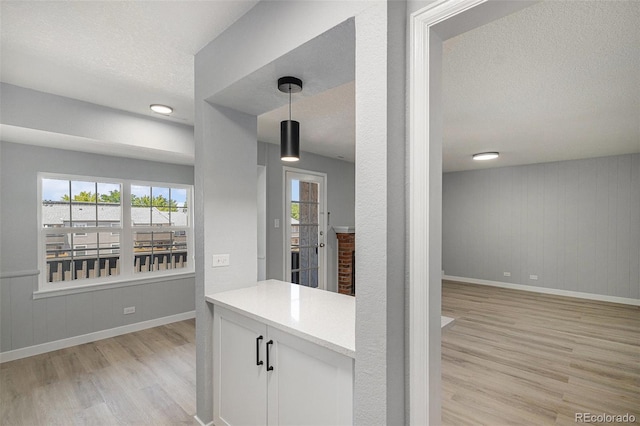 7165 S Gaylord St Unit H05, Centennial, CO 80122 - kitchen with light wood-type flooring, a textured ceiling, white cabinetry, hanging light fixtures, and light countertops