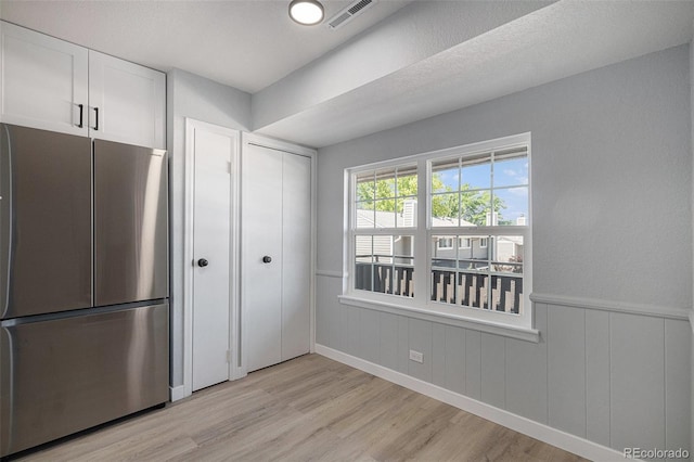 7165 S Gaylord St Unit H05, Centennial, CO 80122 - kitchen featuring freestanding refrigerator, light wood-type flooring, white cabinets, and wainscoting