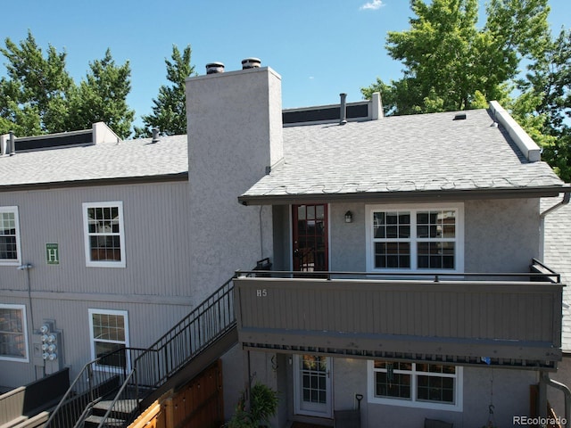 7165 S Gaylord St Unit H05, Centennial, CO 80122 - back of property with a chimney, stairs, roof with shingles, and stucco siding