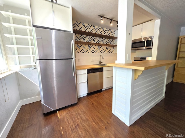 kitchen featuring dark hardwood / wood-style flooring, a textured ceiling, decorative backsplash, white cabinets, and appliances with stainless steel finishes