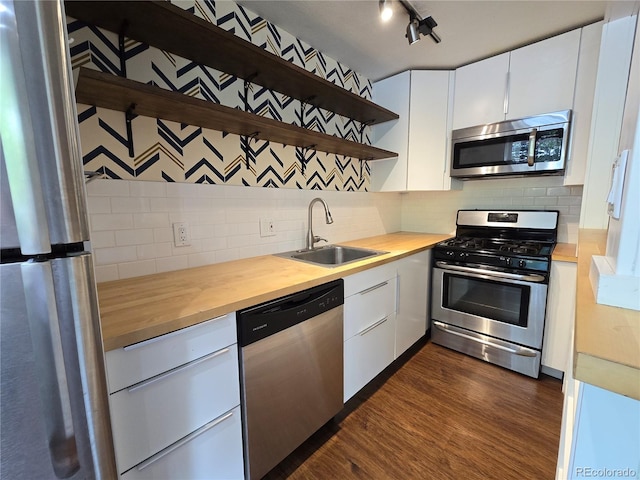 kitchen featuring stainless steel appliances, white cabinetry, butcher block counters, and sink