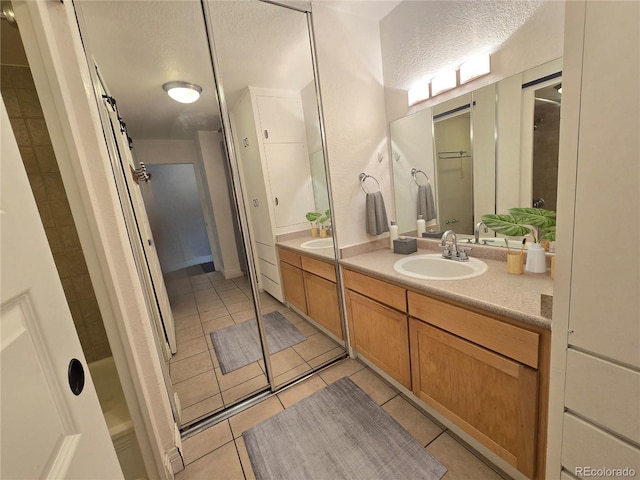 bathroom featuring vanity, a textured ceiling, tile patterned floors, and walk in shower