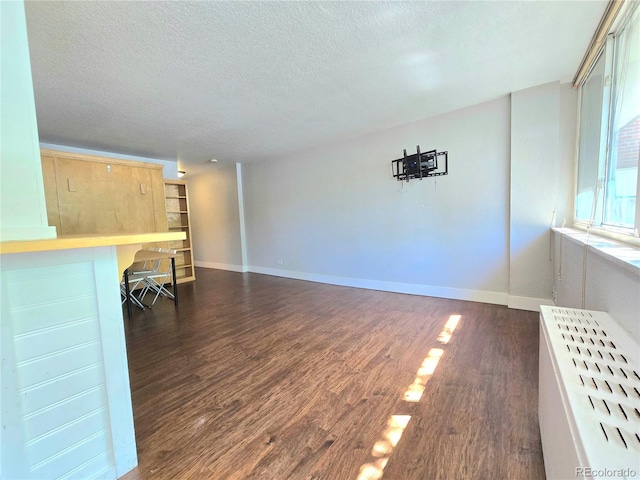 unfurnished living room with dark wood-type flooring and a textured ceiling