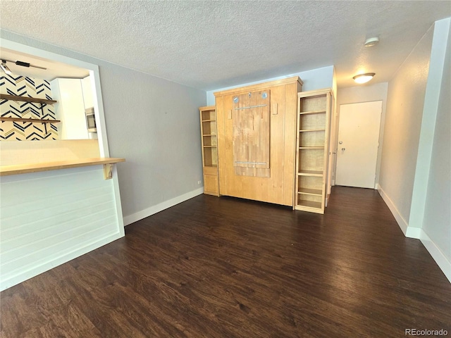 unfurnished living room featuring a textured ceiling and dark hardwood / wood-style floors