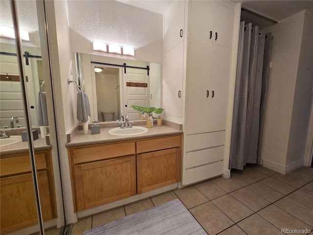 bathroom featuring tile patterned flooring, vanity, toilet, and a textured ceiling