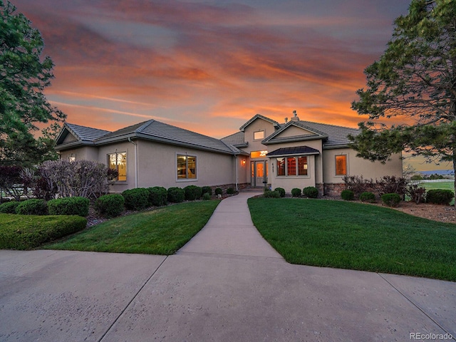 view of front of home with a lawn, stucco siding, and a tile roof