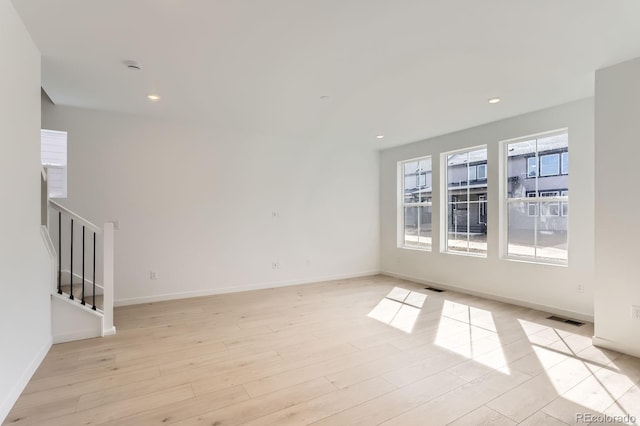 spare room with light wood finished floors, visible vents, baseboards, stairs, and recessed lighting