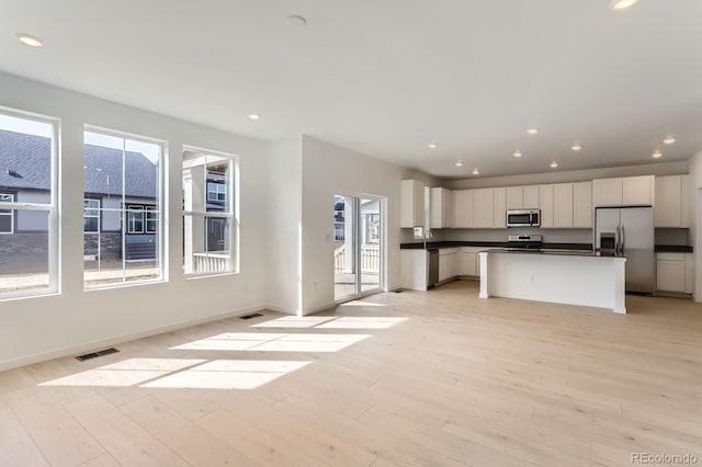 kitchen with visible vents, light wood-style flooring, stainless steel appliances, white cabinets, and dark countertops