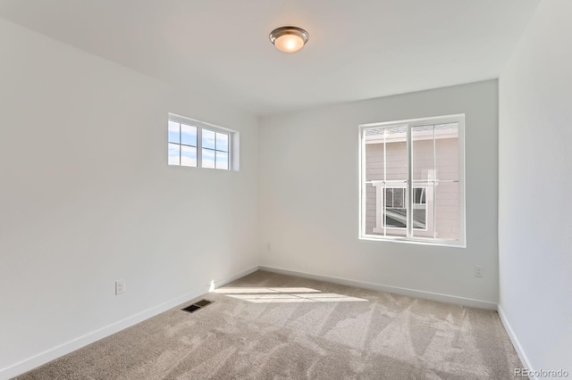 empty room featuring carpet, visible vents, and baseboards