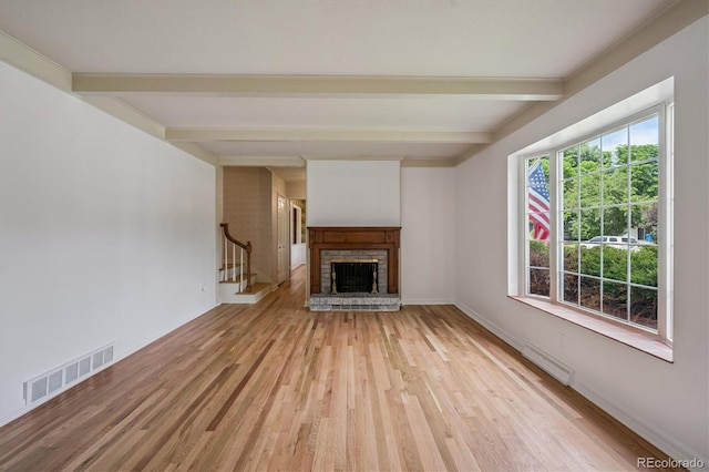 3225 S Race St, Englewood, CO 80113 - unfurnished living room with beamed ceiling, light wood-style flooring, a fireplace with raised hearth, and stairway