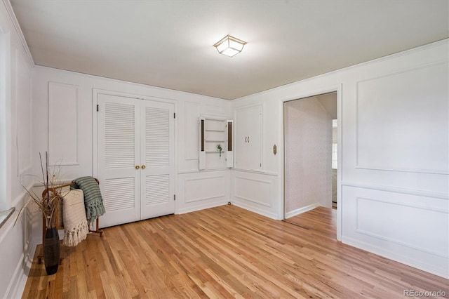 3225 S Race St, Englewood, CO 80113 - unfurnished bedroom featuring light wood-type flooring, a decorative wall, and a closet