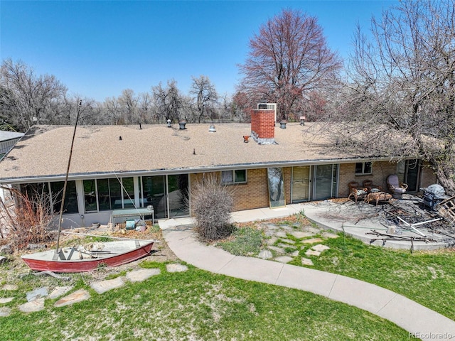 rear view of property featuring a patio area, a sunroom, and a lawn