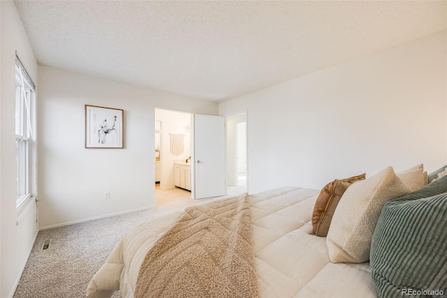 carpeted bedroom featuring a textured ceiling and connected bathroom