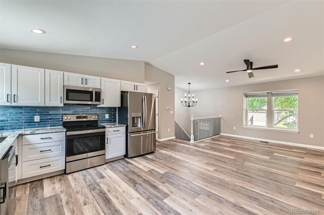 6040 W 75th Dr, Arvada, CO 80003 - kitchen featuring appliances with stainless steel finishes, vaulted ceiling, a chandelier, light wood-style flooring, and backsplash