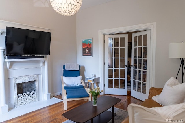 living area with wood finished floors, french doors, and a fireplace