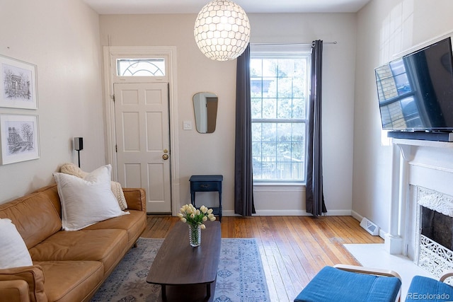 living room with a premium fireplace, a wealth of natural light, baseboards, and light wood-style flooring