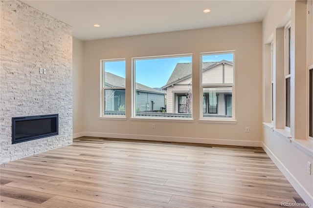 unfurnished living room featuring light hardwood / wood-style floors and a stone fireplace