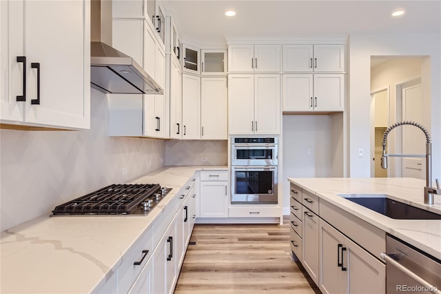 kitchen with white cabinetry, sink, light stone countertops, and stainless steel appliances