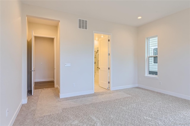 unfurnished bedroom with connected bathroom and light colored carpet