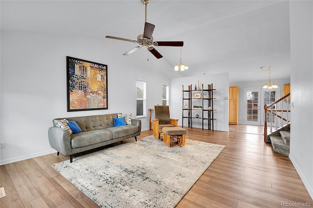 living room featuring light wood-style flooring, stairway, vaulted ceiling, and ceiling fan with notable chandelier