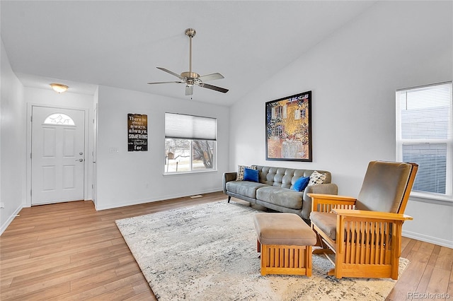 living area featuring lofted ceiling, light wood-style floors, baseboards, and a ceiling fan