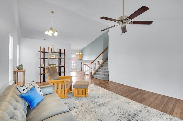 living area with vaulted ceiling, stairway, wood finished floors, and baseboards