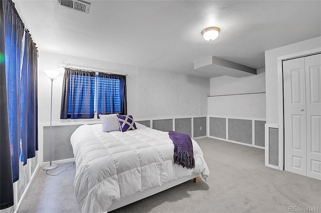 carpeted bedroom with visible vents and a closet