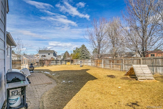 view of yard featuring an outbuilding, a fenced backyard, a residential view, a patio area, and an exterior structure