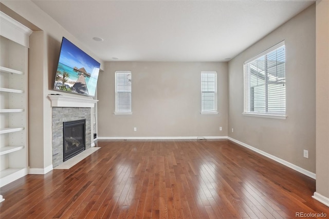 unfurnished living room featuring built in features, a fireplace, and dark wood-type flooring