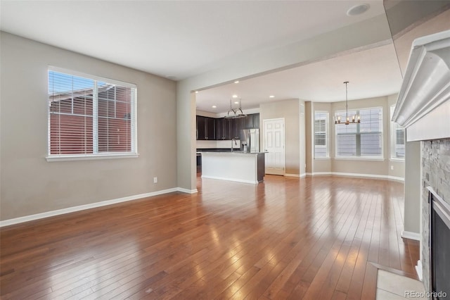 unfurnished living room with a notable chandelier, sink, and dark wood-type flooring