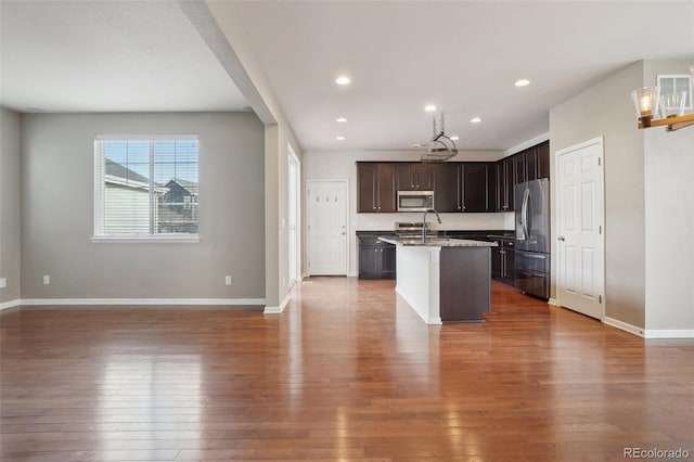 kitchen with dark brown cabinetry, a kitchen island with sink, dark hardwood / wood-style floors, and appliances with stainless steel finishes