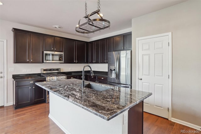 kitchen featuring sink, stainless steel appliances, decorative light fixtures, a kitchen island with sink, and hardwood / wood-style flooring