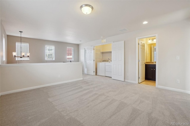 empty room with separate washer and dryer, light colored carpet, and a notable chandelier