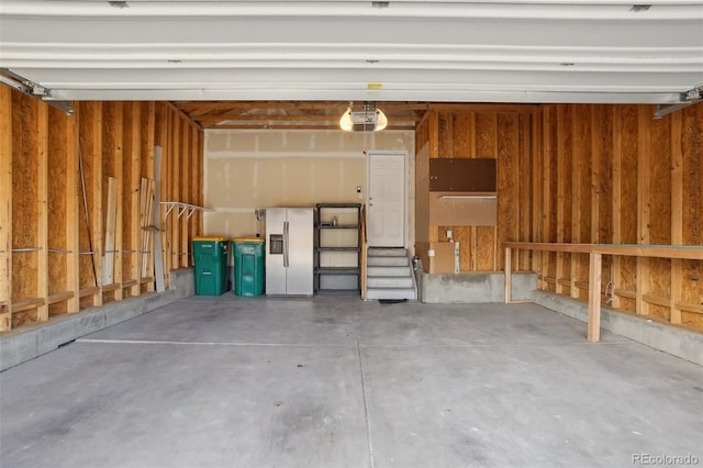 garage featuring white refrigerator with ice dispenser and a garage door opener