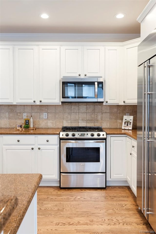 538 Cook St, Denver, CO 80206 - kitchen featuring stainless steel appliances, white cabinetry, light wood finished floors, backsplash, and ornamental molding