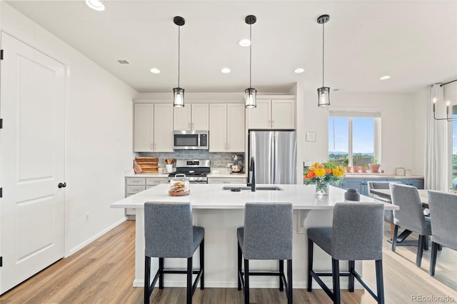 21 N Edge Cliff St, Castle Rock, CO 80104 - kitchen with appliances with stainless steel finishes, decorative backsplash, a sink, light countertops, and a kitchen bar