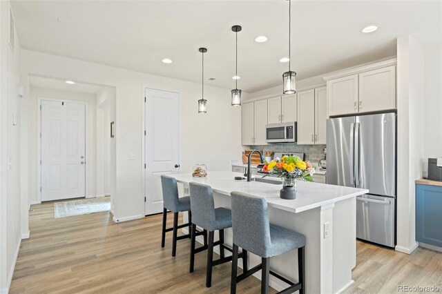 21 N Edge Cliff St, Castle Rock, CO 80104 - kitchen featuring stainless steel appliances, light wood finished floors, light countertops, a breakfast bar, and recessed lighting