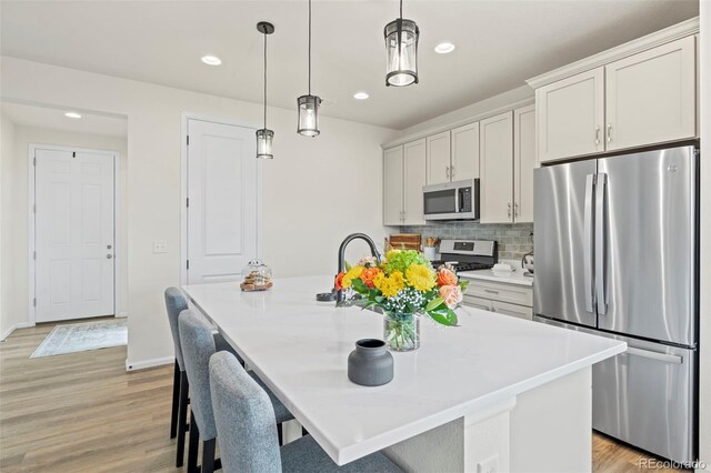 21 N Edge Cliff St, Castle Rock, CO 80104 - kitchen featuring stainless steel appliances, an island with sink, light wood-type flooring, recessed lighting, and light countertops