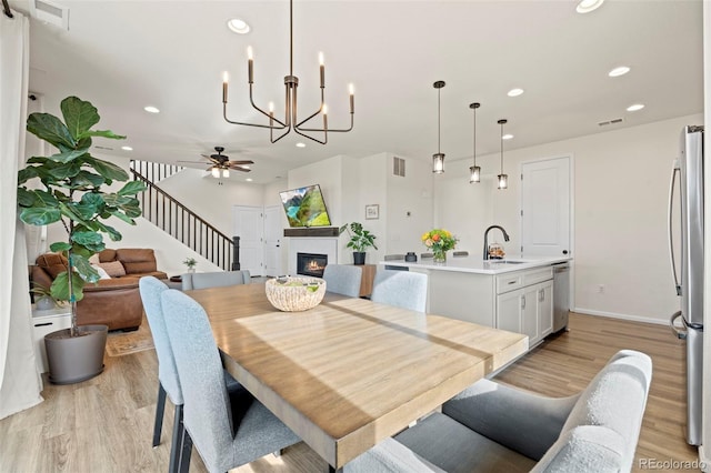 21 N Edge Cliff St, Castle Rock, CO 80104 - dining space featuring stairs, light wood-type flooring, a chandelier, recessed lighting, and a glass covered fireplace