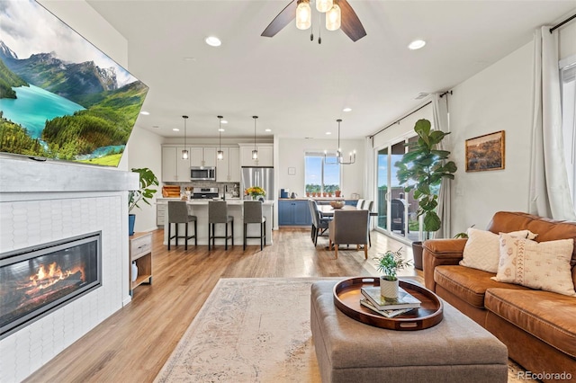 21 N Edge Cliff St, Castle Rock, CO 80104 - living room with light wood-type flooring, a ceiling fan, recessed lighting, and a tiled fireplace