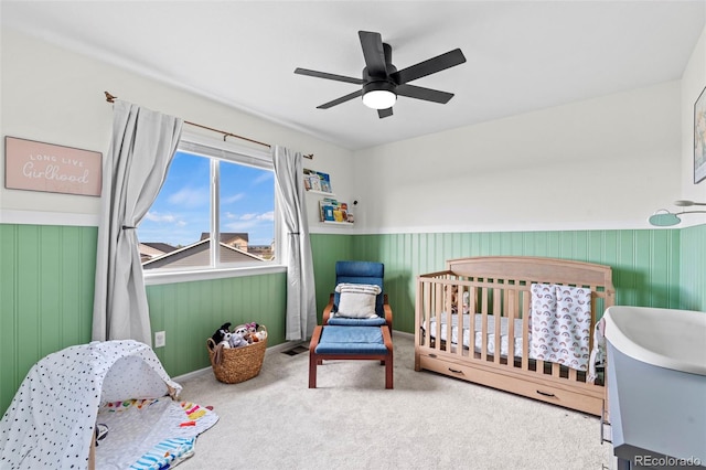 21 N Edge Cliff St, Castle Rock, CO 80104 - bedroom with a crib, a wainscoted wall, carpet, and a ceiling fan