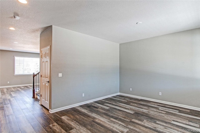 spare room featuring dark wood-type flooring and a textured ceiling