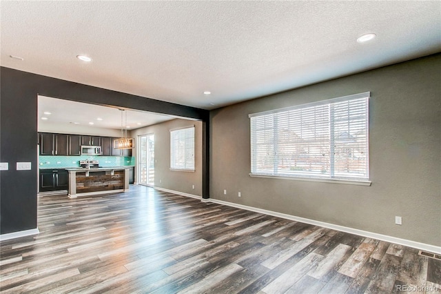 unfurnished living room with dark wood-type flooring and a textured ceiling