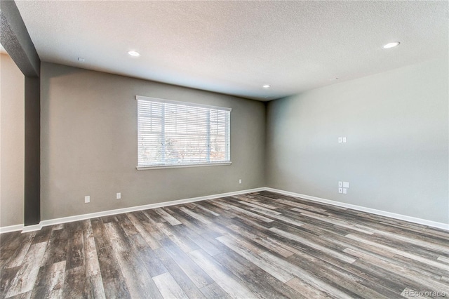 empty room with dark wood-type flooring and a textured ceiling